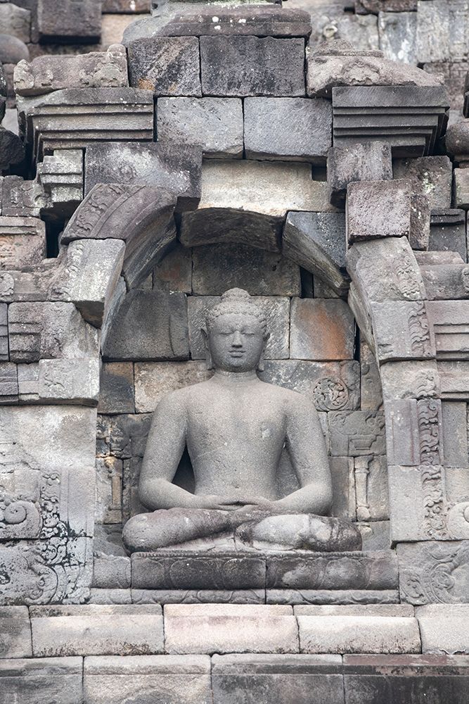 Indonesia-Java-Borobudur. Largest Buddhist monument in the world. Buddha statue in ornate wall.